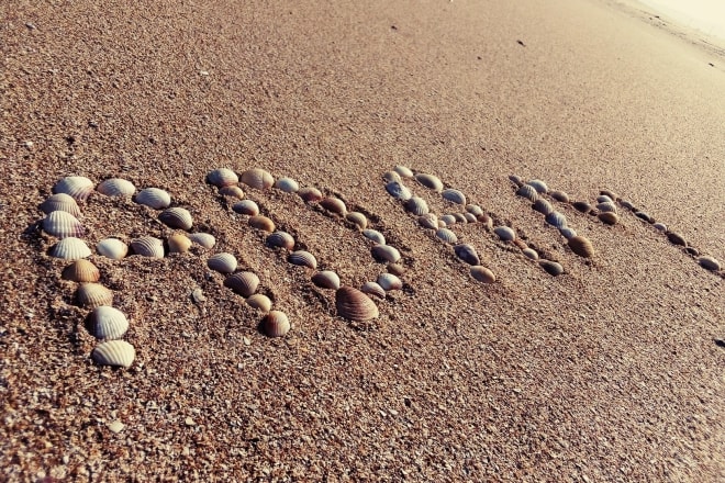 I will write your text on sand with natural shells and beach stones